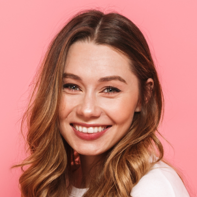 A smiling young woman with long wavy hair against a pink background.